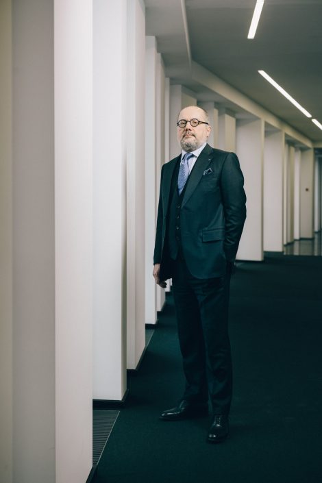 CEO a.D. der Linde AG, Aldo Belloni stehend in einem Ganz mit weißen Säulen und schwarzem Teppich.