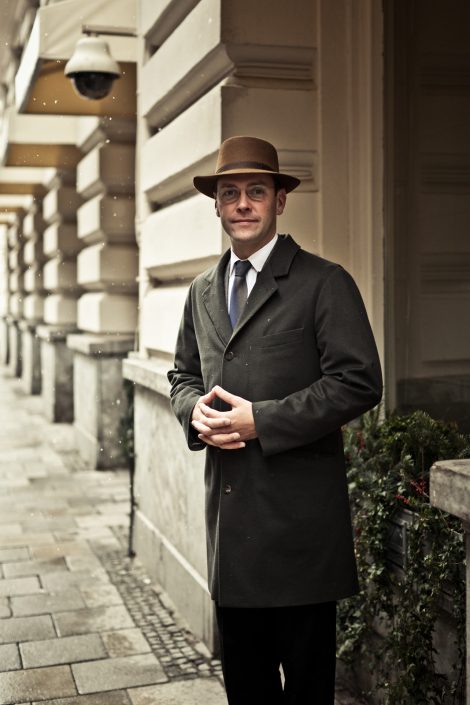 Portrait von James Murdoch mit Mantel und Hut