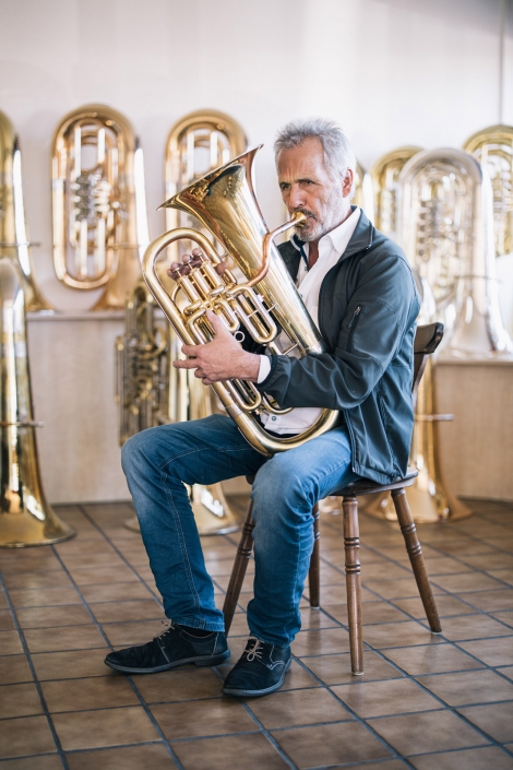 Josef Lindlmair, Vorstandsmitglied der Miraphone eG spielt sitzend auf einer Tuba.