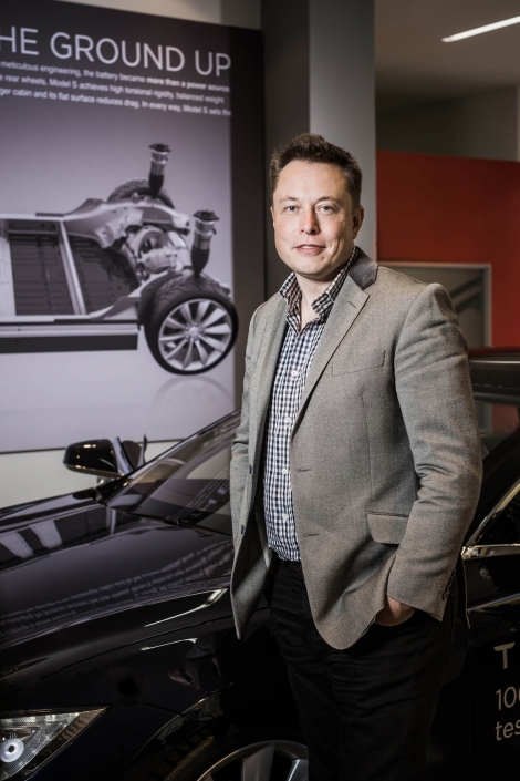 Elon Musk mit Sakko vor einem Tesla Model S.